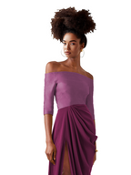 Woman wearing a purple off-shoulder dress with a draped design on a white background