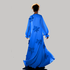 Person wearing a long blue dress with floral patterns on a gray background
