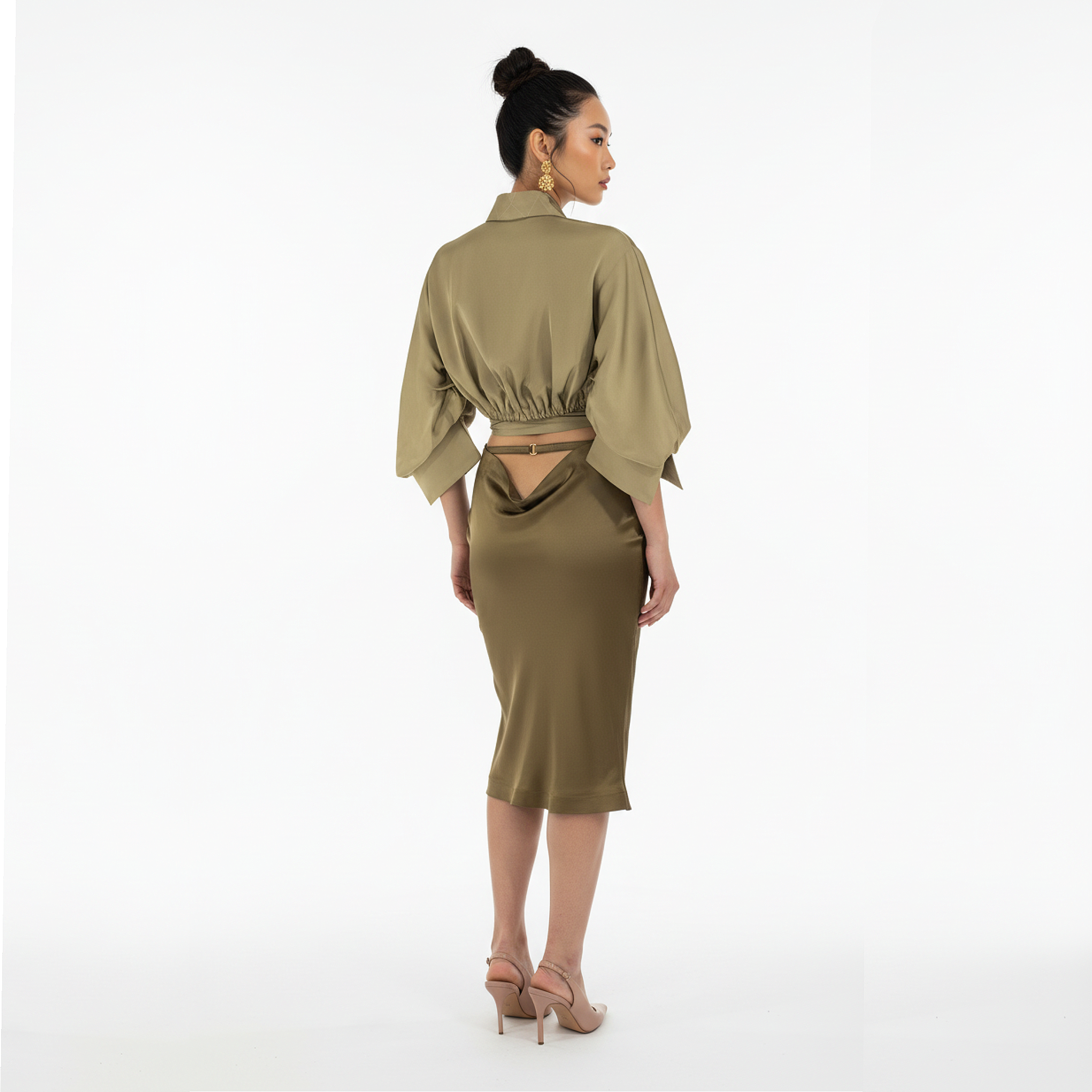 Woman wearing a green dress with cut-out back on a white background