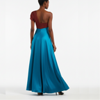 Woman wearing a one-shoulder red top and long blue dress on a white background