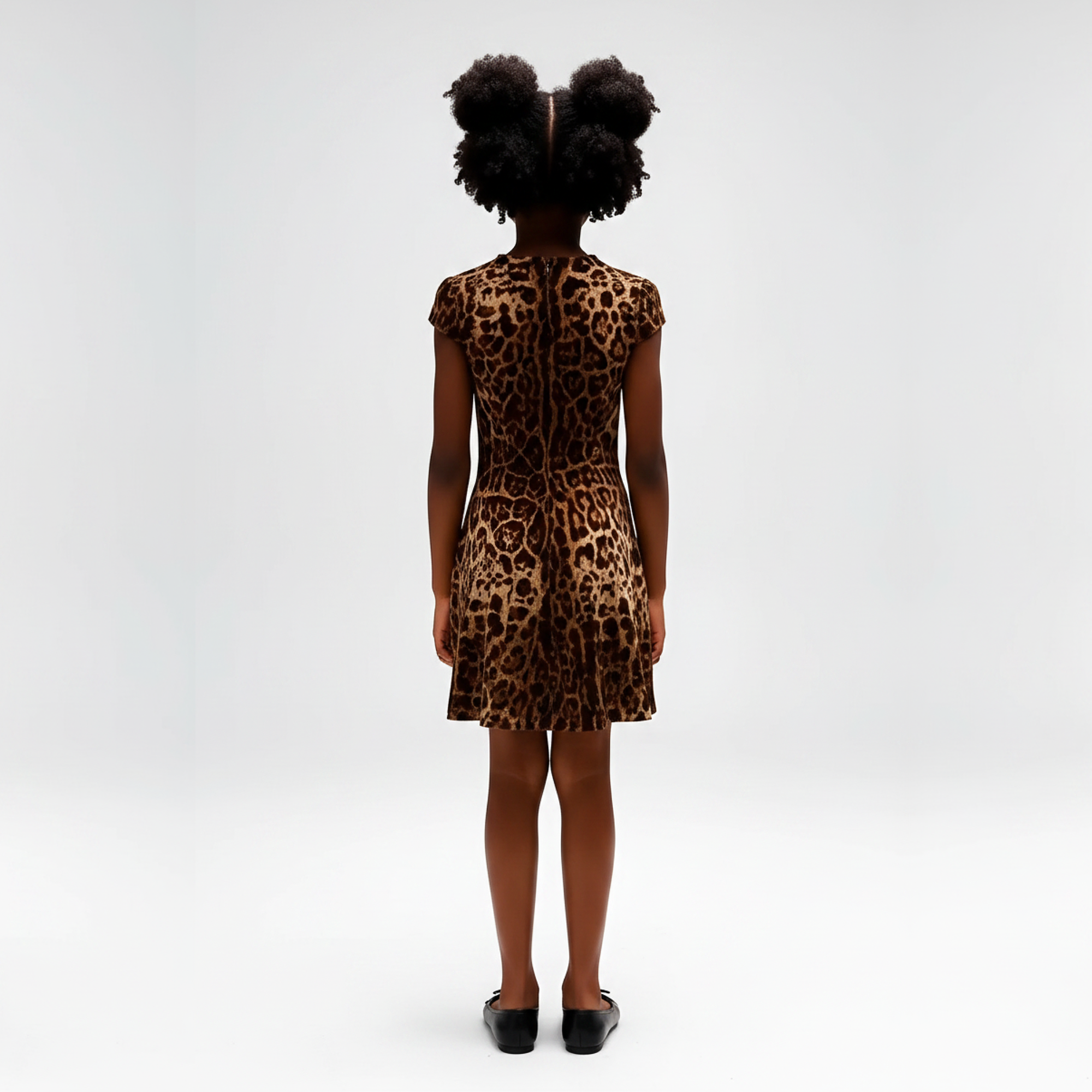 Child wearing a leopard print dress with a large black bow on a gray background