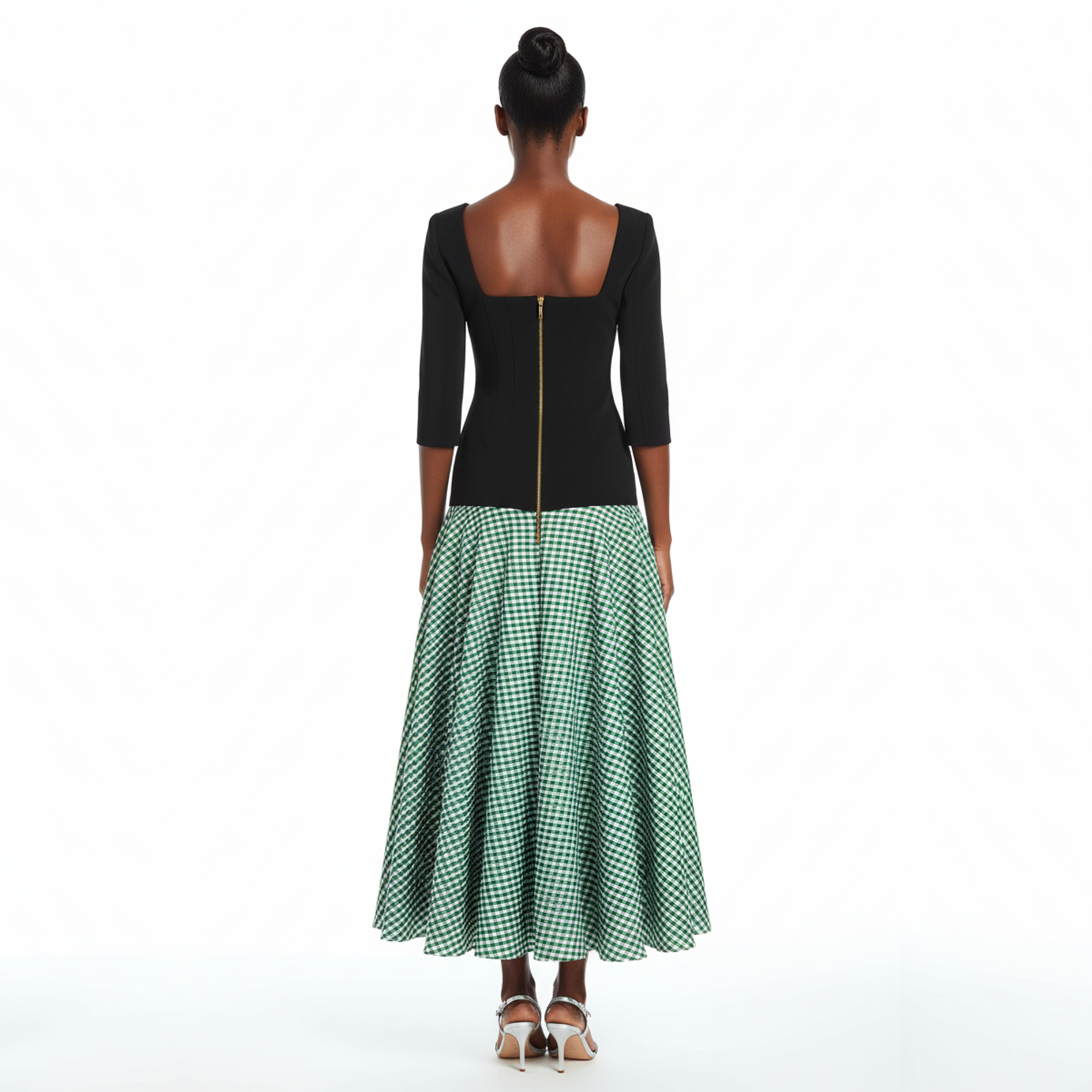 Woman wearing a black top and green checkered skirt on a white background