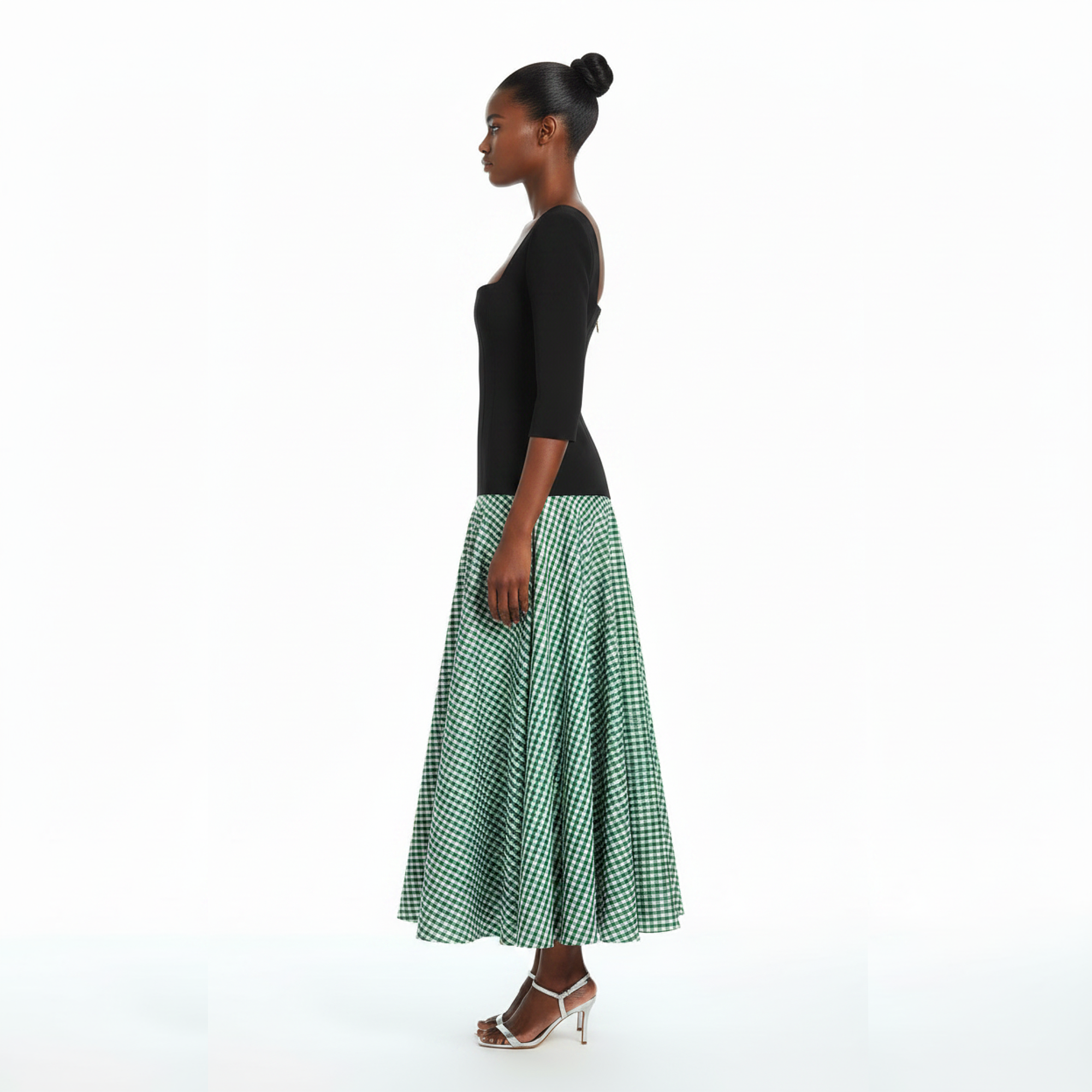 Woman wearing a black top and green checkered skirt on a white background