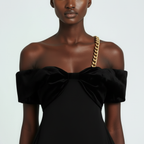 Black off-shoulder dress with a large bow detail on a plain background