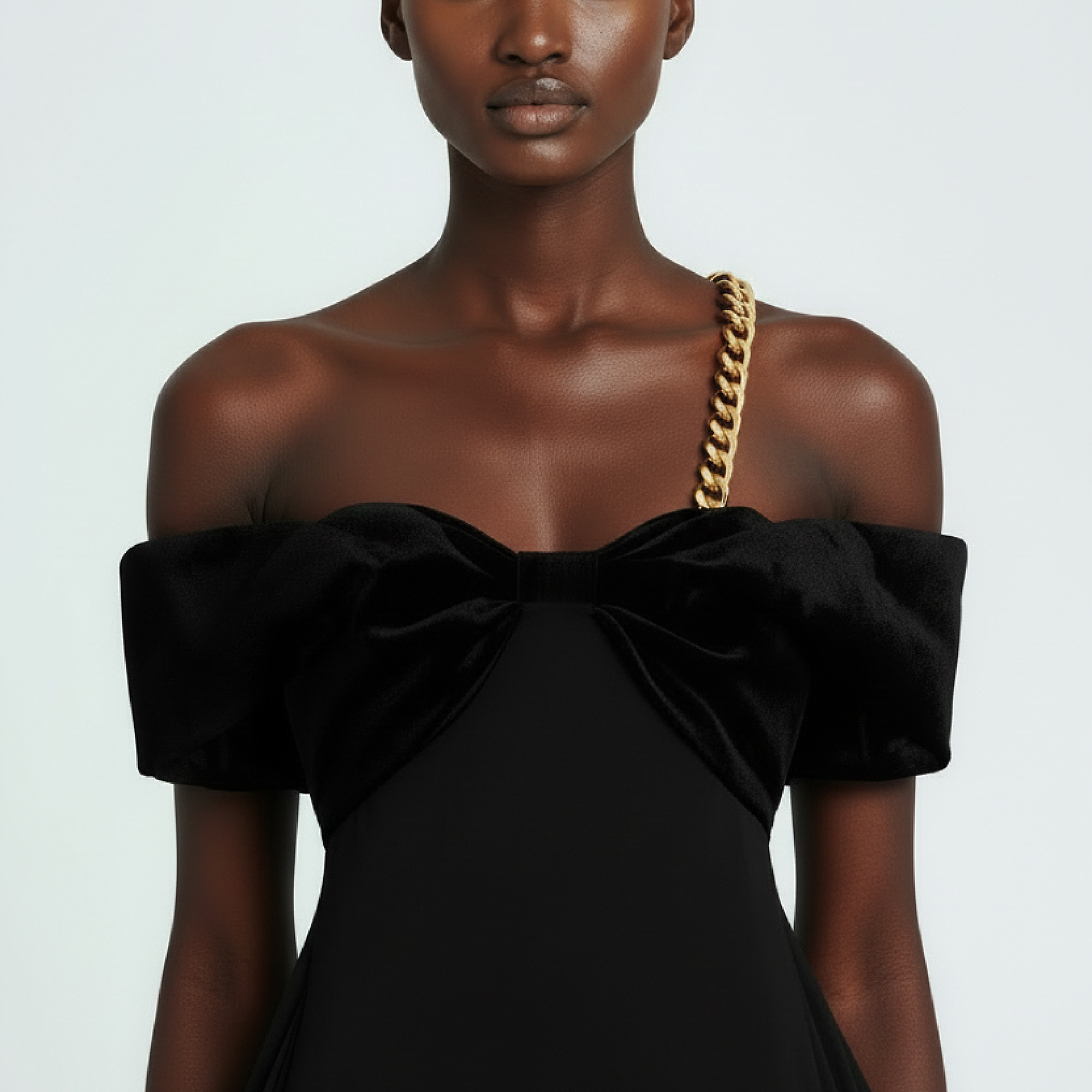 Black off-shoulder dress with a large bow detail on a plain background
