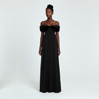 Woman wearing a black off-shoulder gown with a gold chain on a white background