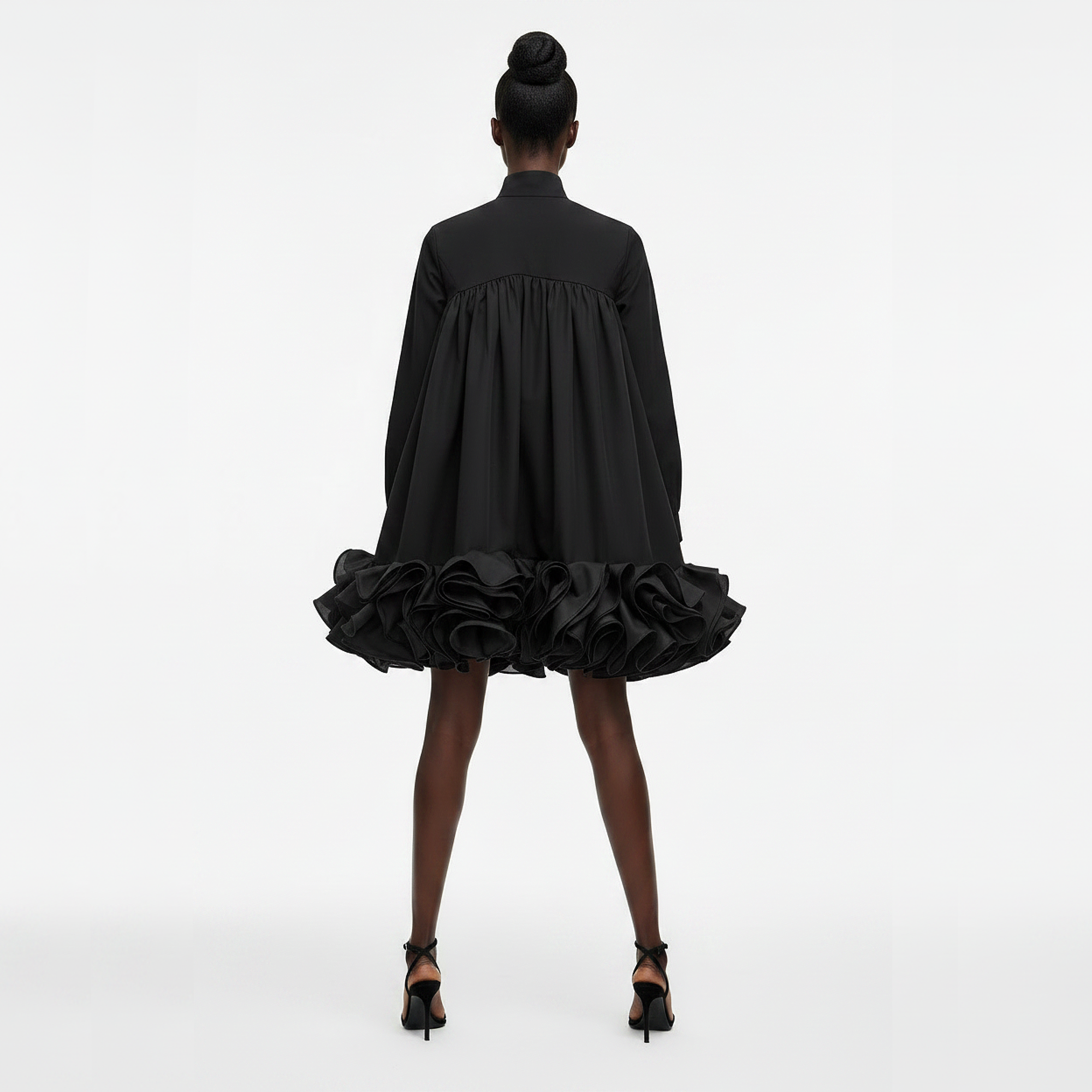 Black dress with ruffled skirt worn by a model on a white background