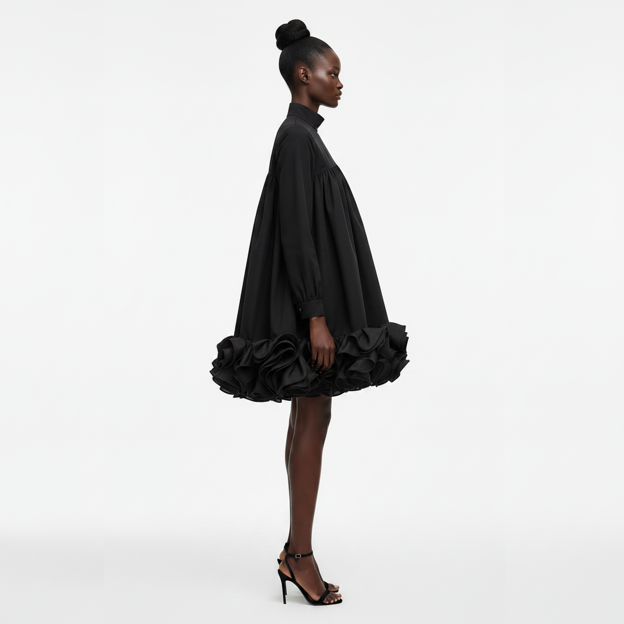Woman wearing a black dress with ruffled skirt on a white background