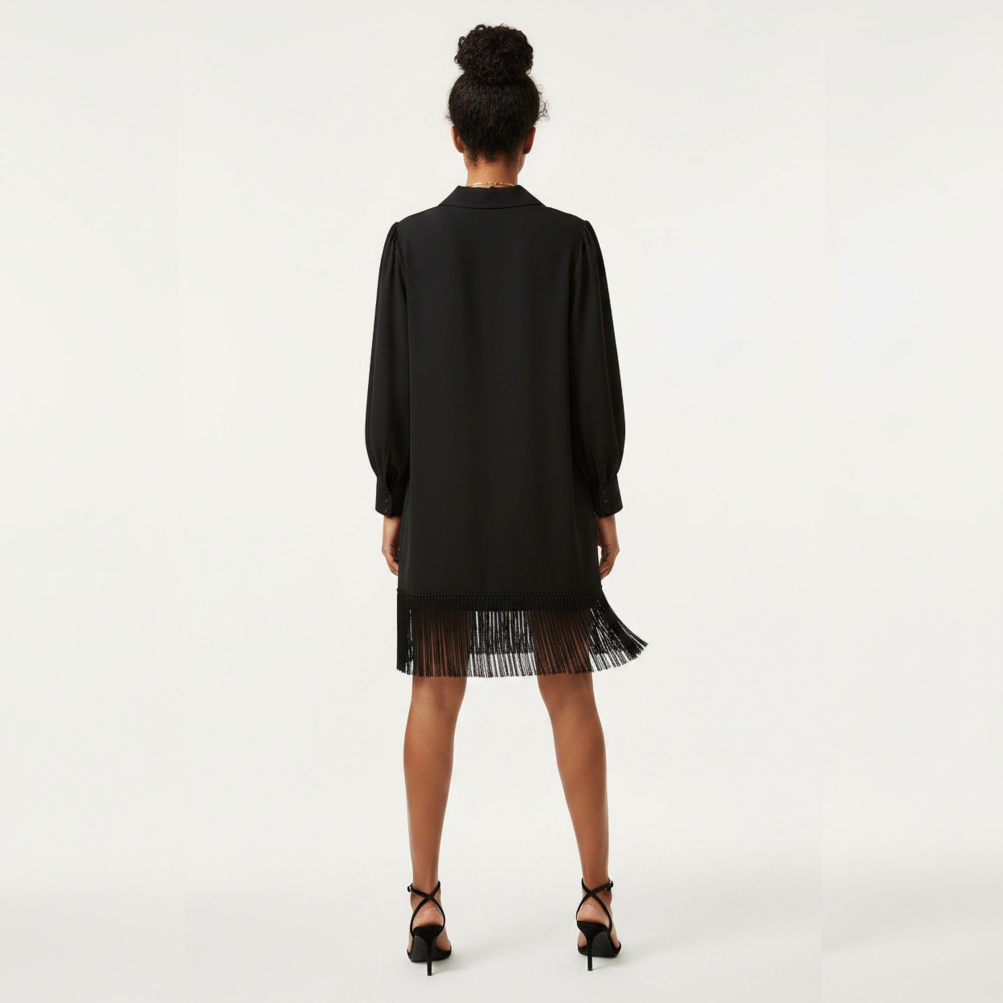 Woman wearing a black dress with a fringed hem on a white background