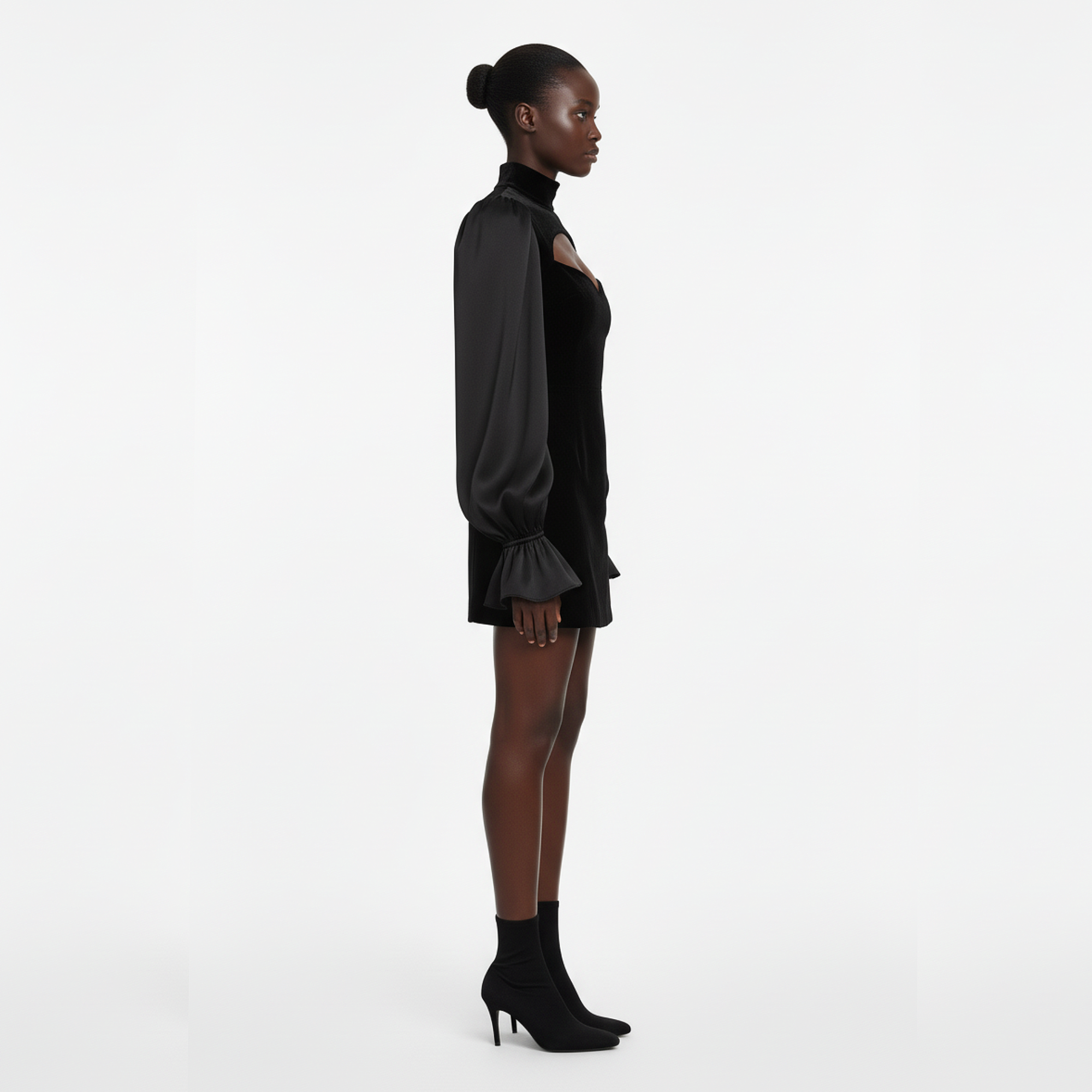 Woman wearing a black outfit with long sleeves and high heels on a white background