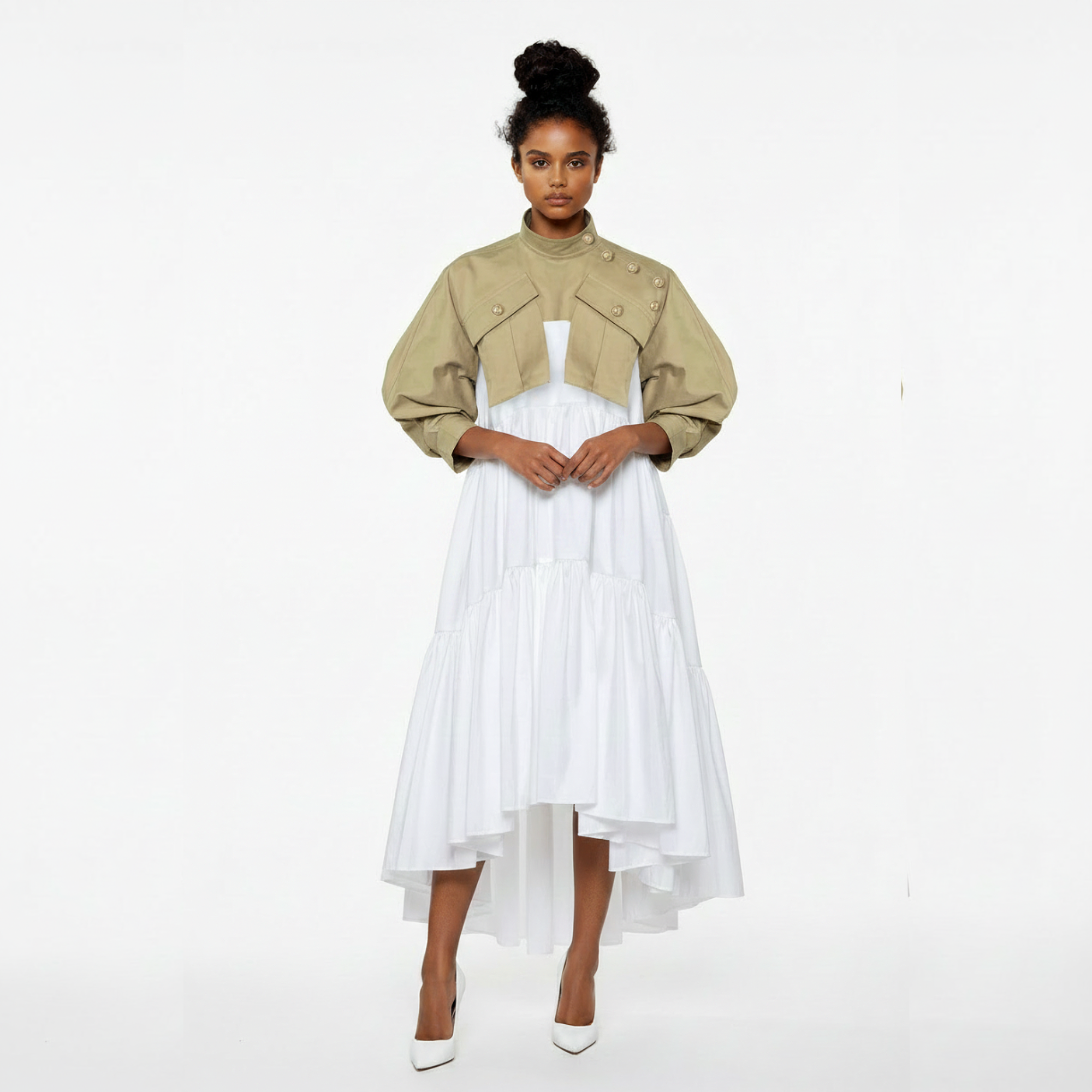 Woman wearing a beige cropped jacket over a white dress on a white background