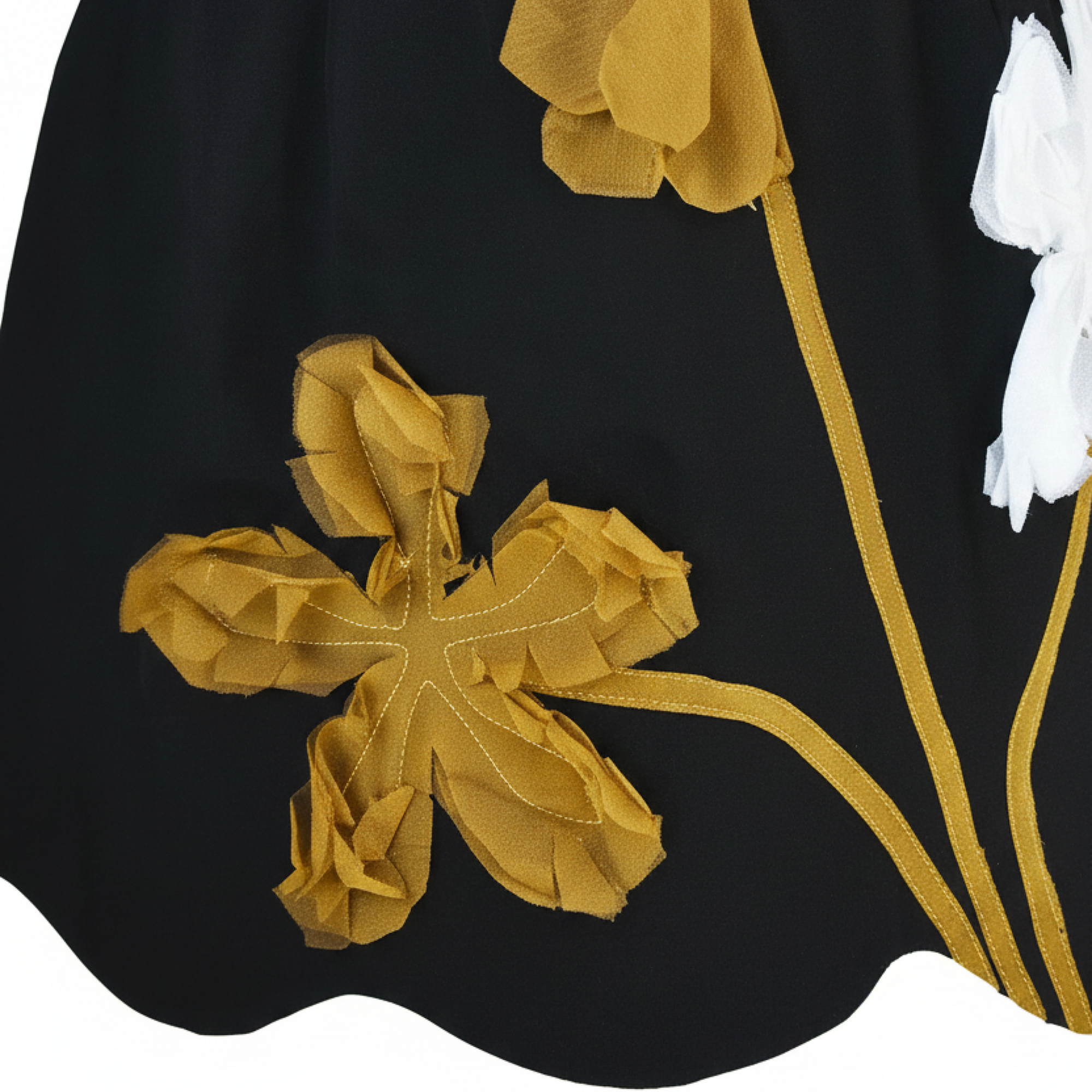 Close-up of a black fabric with gold floral embroidery on a white background