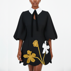 Black dress with floral embroidery on a white background