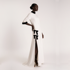 Woman wearing a white dress with black accents on a plain background