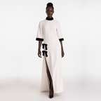 Model wearing a white dress with black accents on a white background