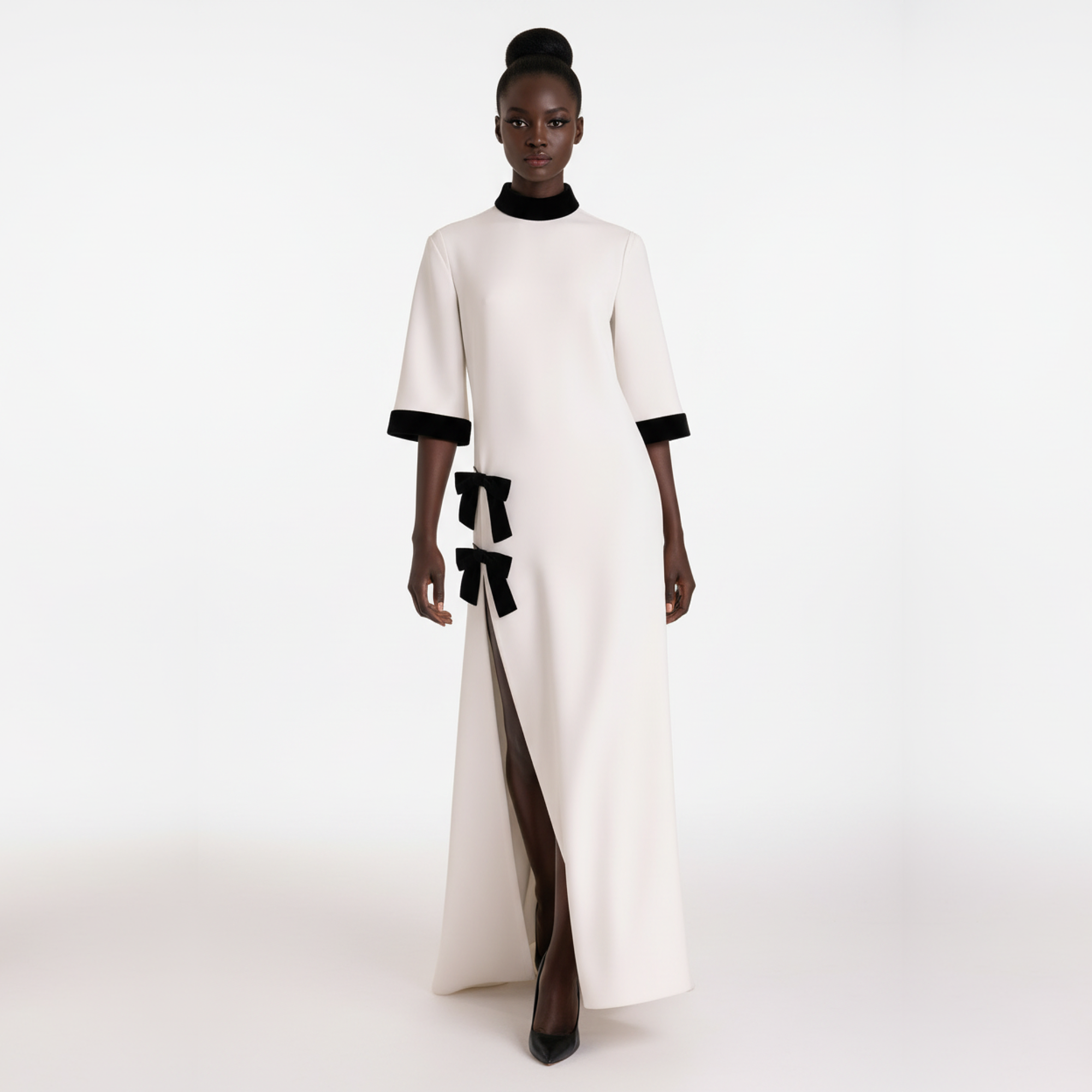 Model wearing a white dress with black accents on a white background