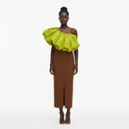 Model wearing a brown dress with a bright green ruffled top on a white background