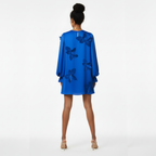 Woman wearing a blue dress with butterfly designs on a white background