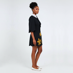Woman wearing a black dress with yellow floral patterns on a white background