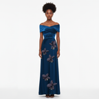 Woman wearing a blue evening gown with floral embellishments on a white background
