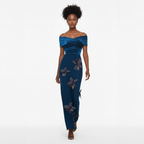 Woman wearing a blue off-shoulder gown with floral embellishments on a white background