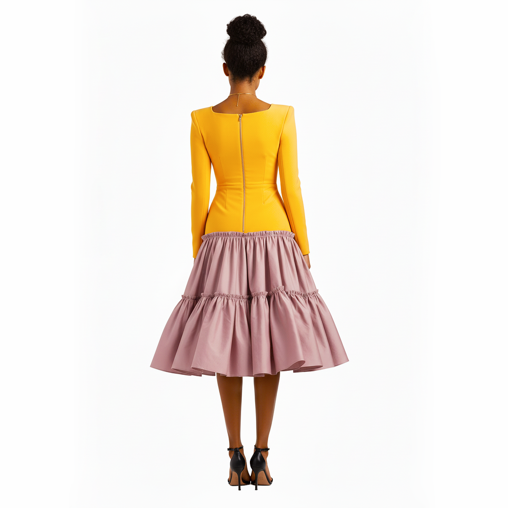 Woman wearing a yellow long-sleeve top and pink ruffled skirt on a white background